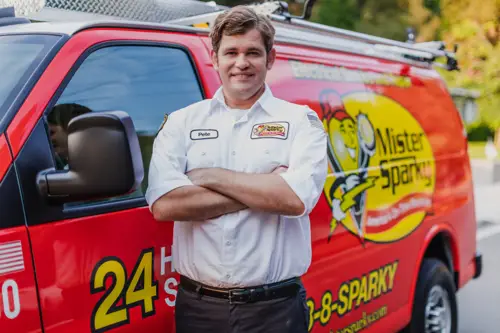 Closeup of Mister Sparky Electrician Tech, Pete, standing in front of his red service van