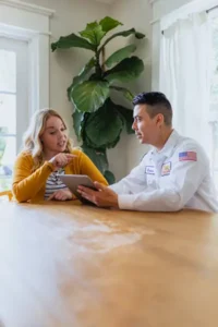 Mister Sparky Electrician Tech, Emilio, speaking with a homeowner at her kitchen table